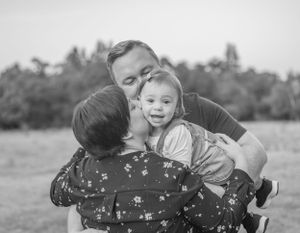 Black and white portrait of family sharing an intimate embrace outdoors.