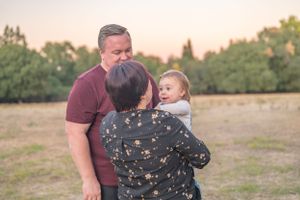Tender family moment captured during outdoor photo session at sunset.
