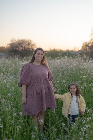 Mother and child standing together in a field of white wildflowers at dusk.