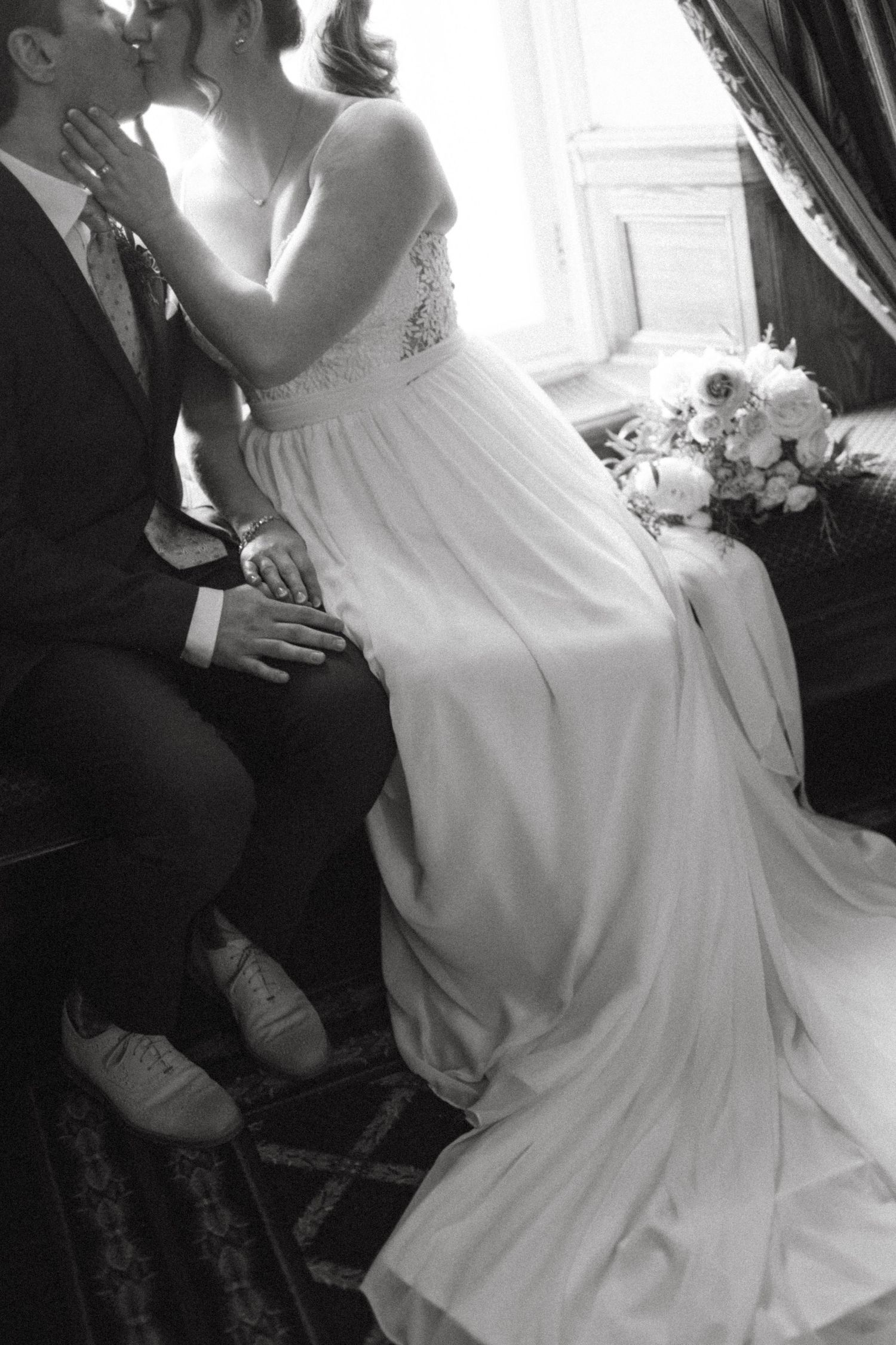 Black and white wedding photograph with flowing white dress and intimate moment.