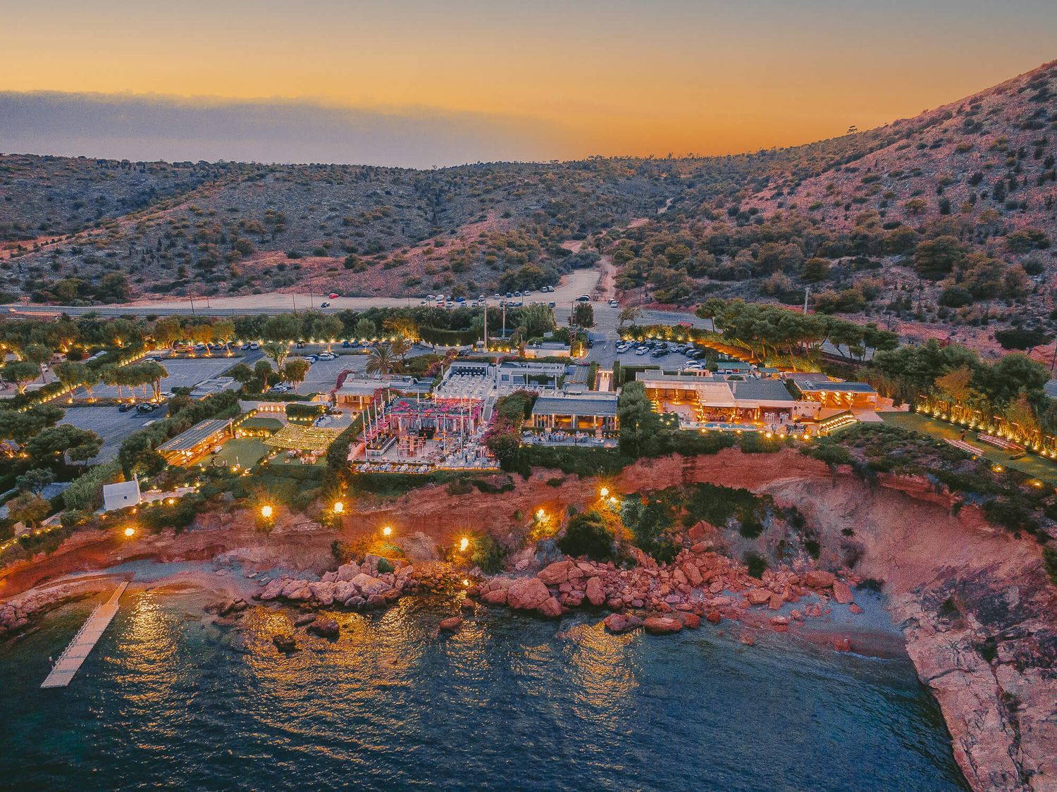 Luxurious beachfront resort illuminated at sunset along rocky Mediterranean coastline on Athens Island Riviera captured By GeorgeNafpliotis