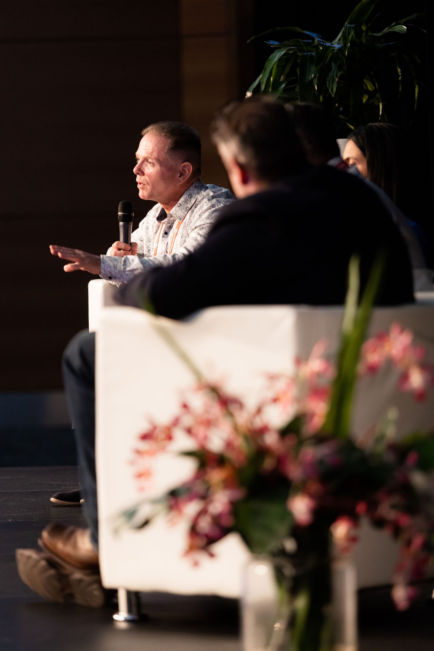 Conference panel discussion setup with floral arrangements and modern white furniture.