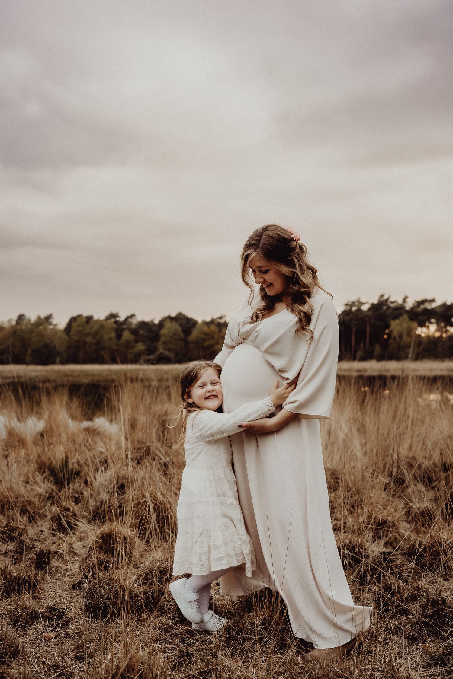 Tender moment captured in sepia tones of mother and child embracing in grassy field.