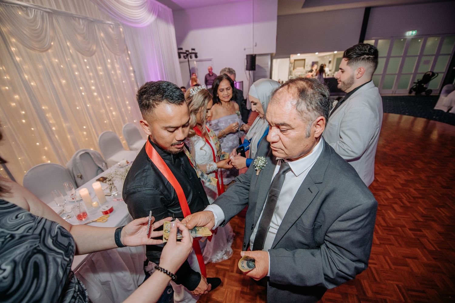 Wedding guests mingle and socialize during reception under decorative string lights.