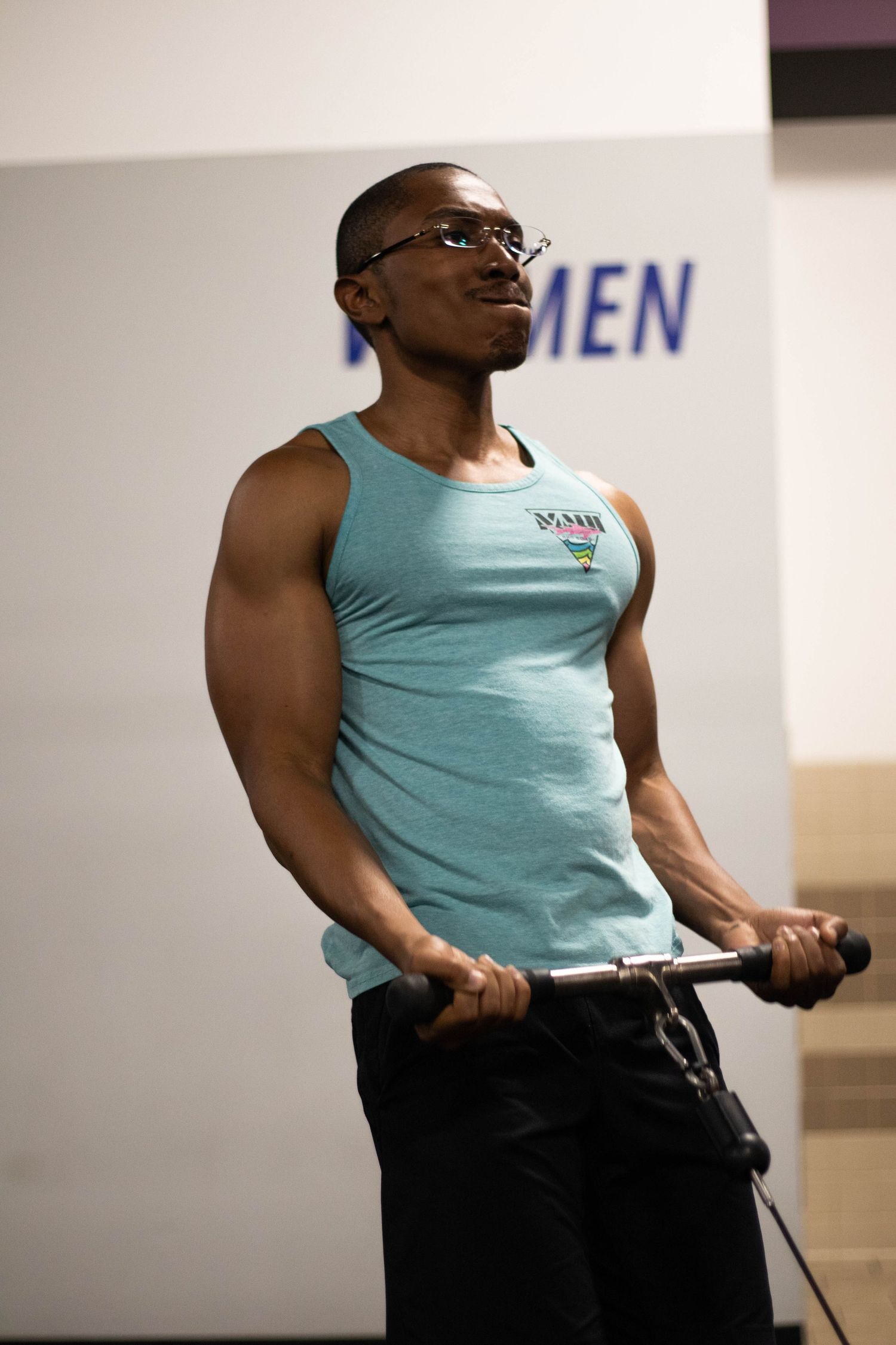 Athletic person exercising with workout equipment in turquoise tank top.