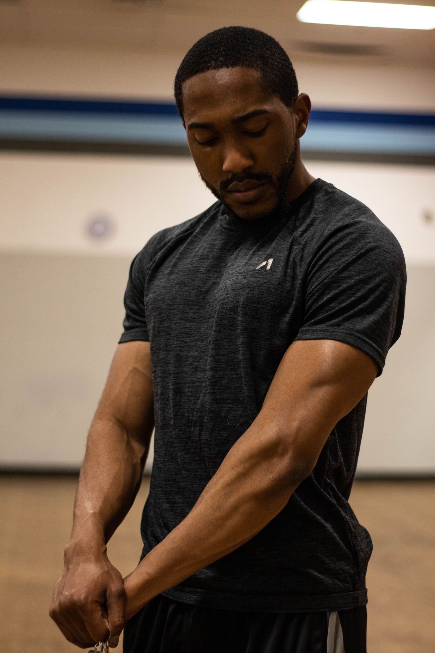Fitness trainer in dark grey athletic shirt demonstrates proper workout form.