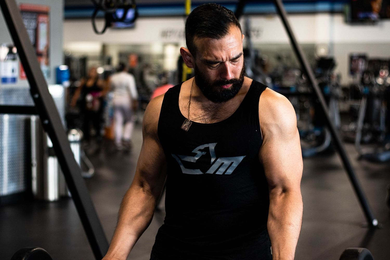 Muscular person wearing a black tank top training in a modern fitness center.