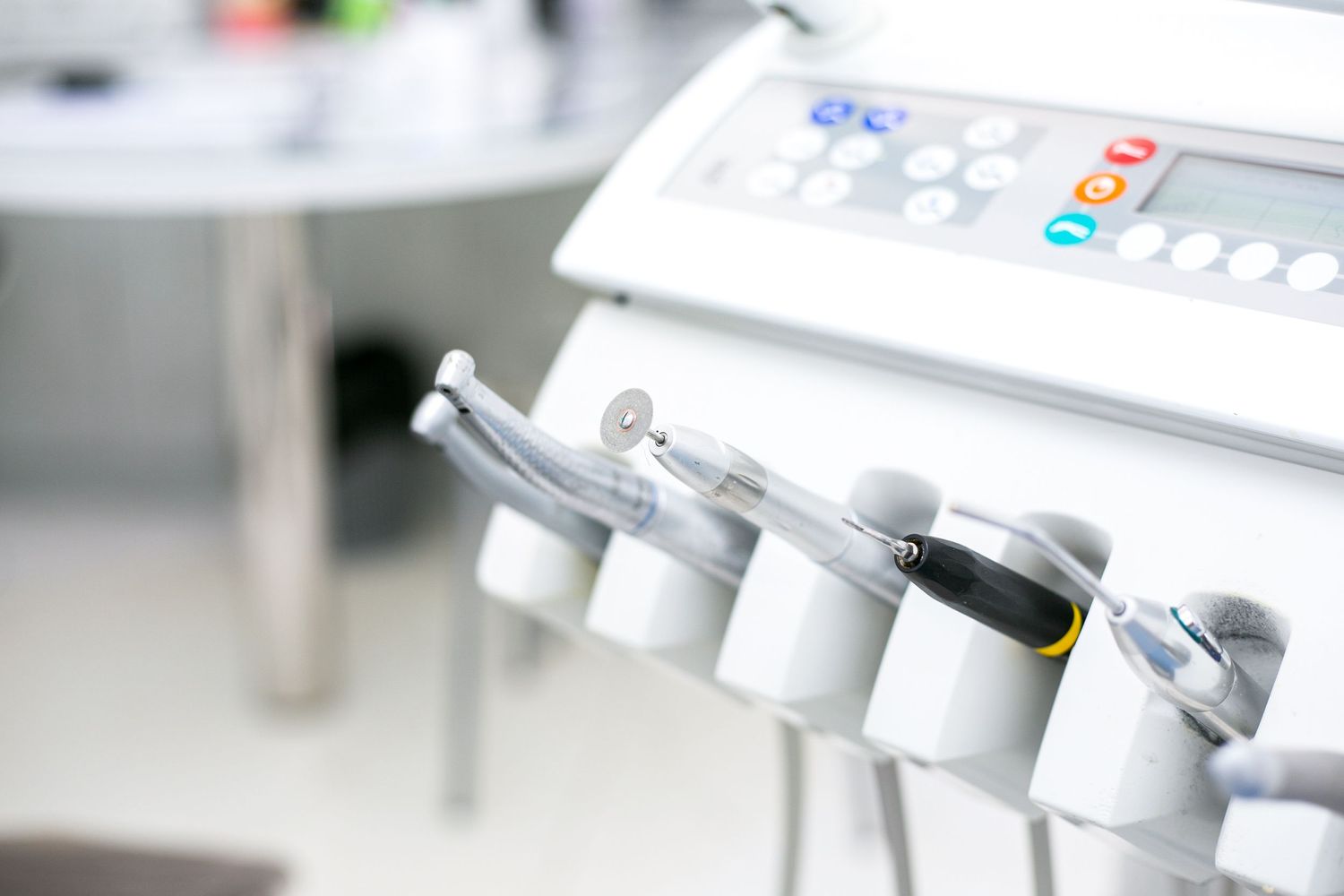 Close-up of dental tools and equipment mounted on a white medical stand.