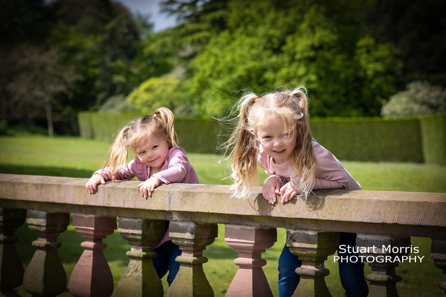 2 young girls climb on the balustrade at Walton hall gardens during their mini portrait session.