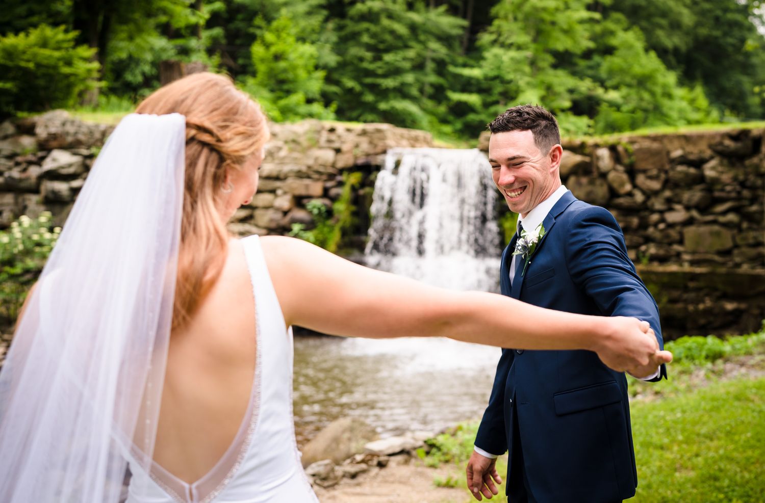 Couple sharing romantic moment by stone waterfall during outdoor wedding photoshoot.