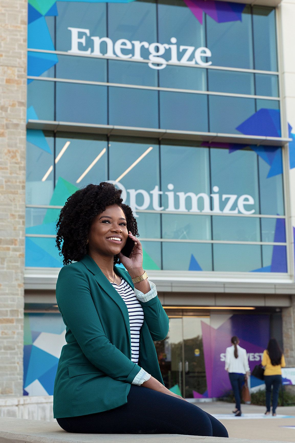 A young woman talks on her phone in front of a building covered in custom graphics installed by FedEx Office.