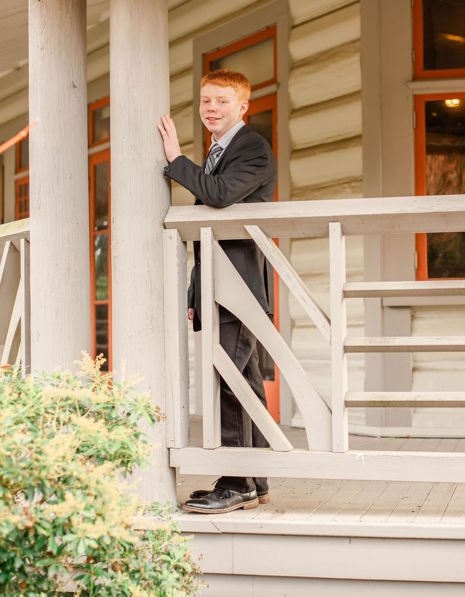 Professional photos showcase a dark suit on concrete steps with white pillars and greenery.