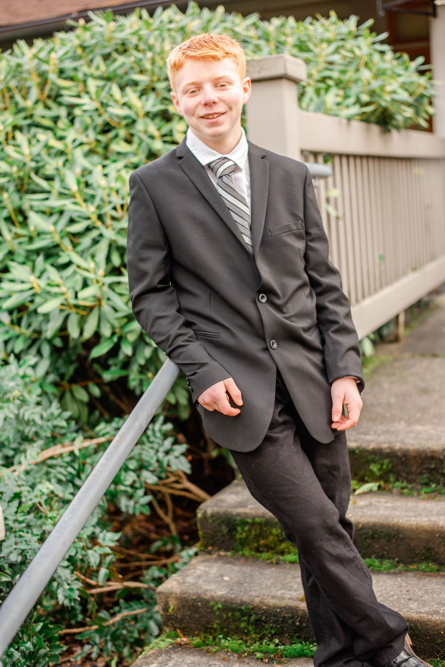 Formal portraits taken by concrete steps with green shrubbery in the background.