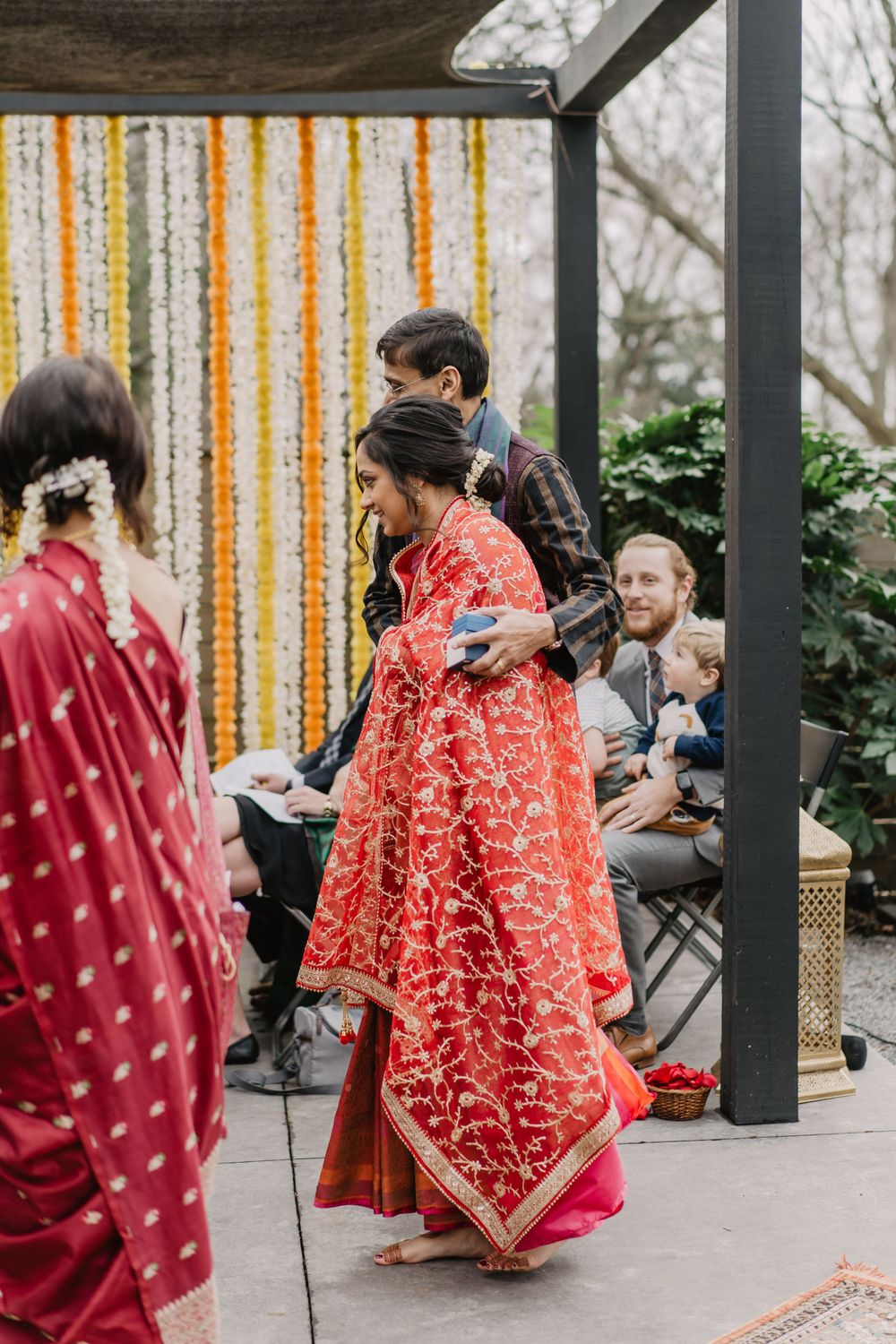 the father walks the bride down the aisle as guests look on