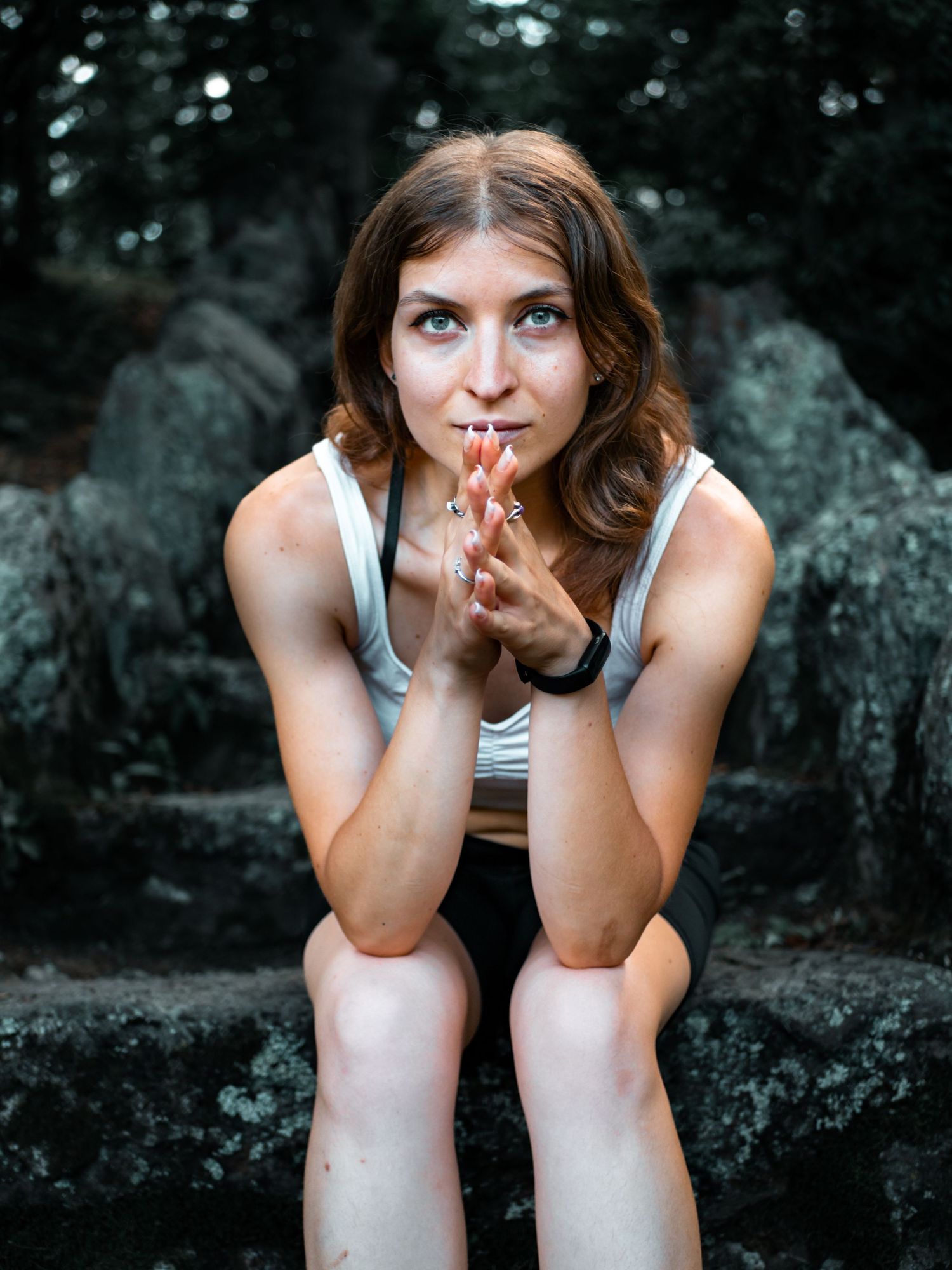 Person sitting on rocky surface in outdoor setting making playful gesture.