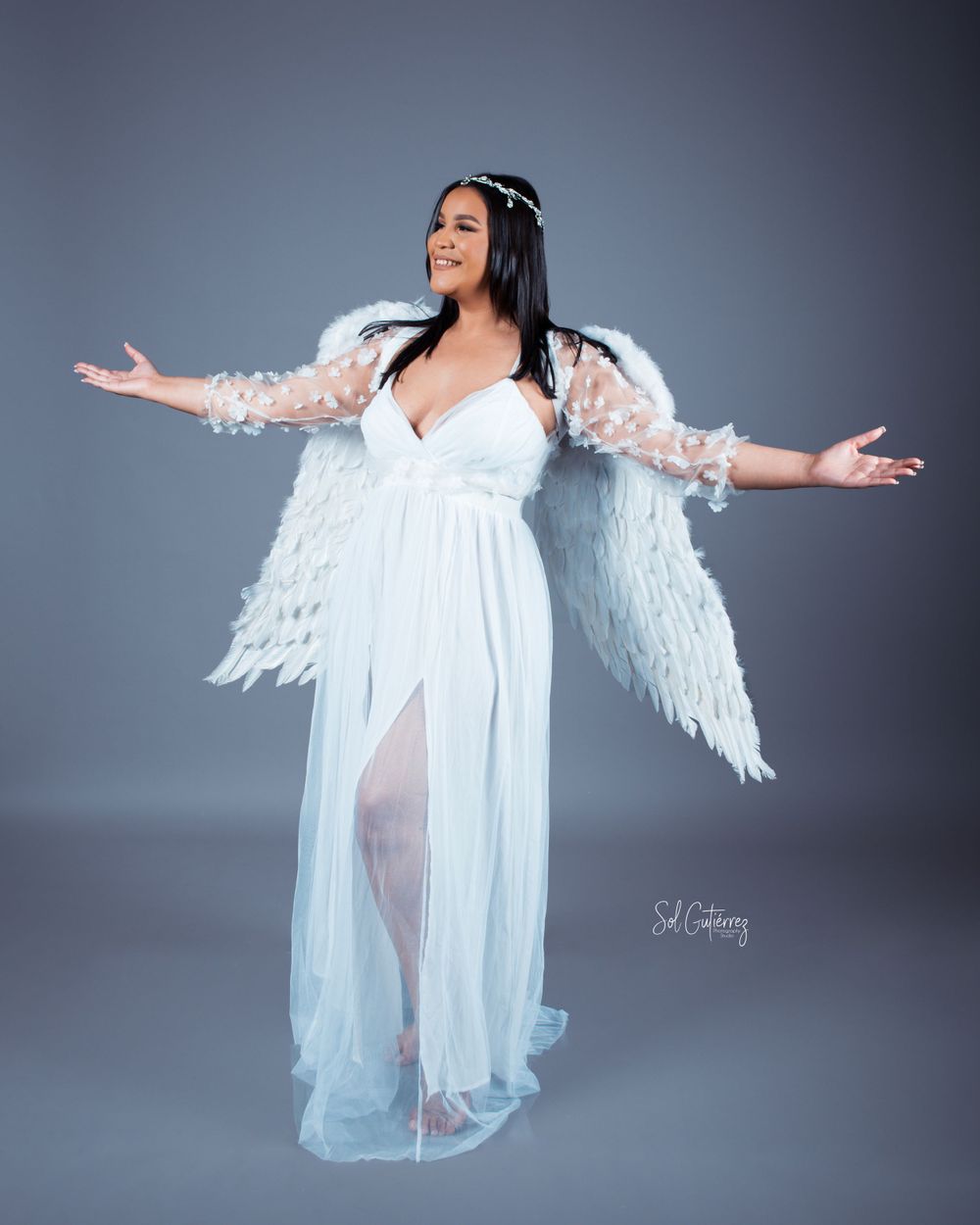 Creative studio portrait in Allentown PA of woman wearing white angel wings and flowing dress with elegant pose.