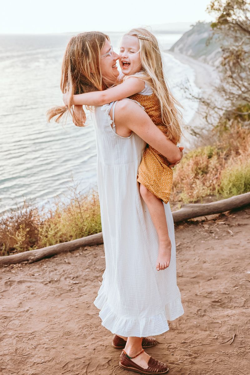 A touching embrace shared between two people at a scenic coastal overlook.