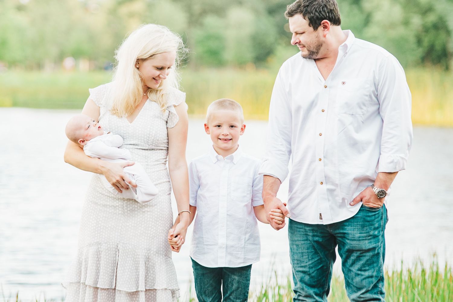 Family portrait session in a sunlit field with natural greenery.