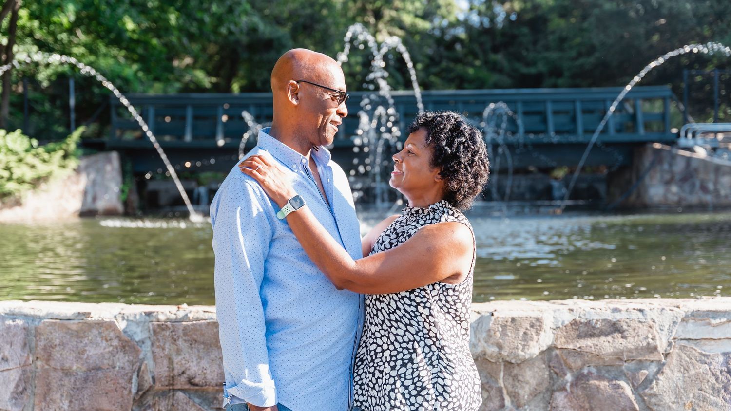 Couple gazing at each other near fountain in sunny park.