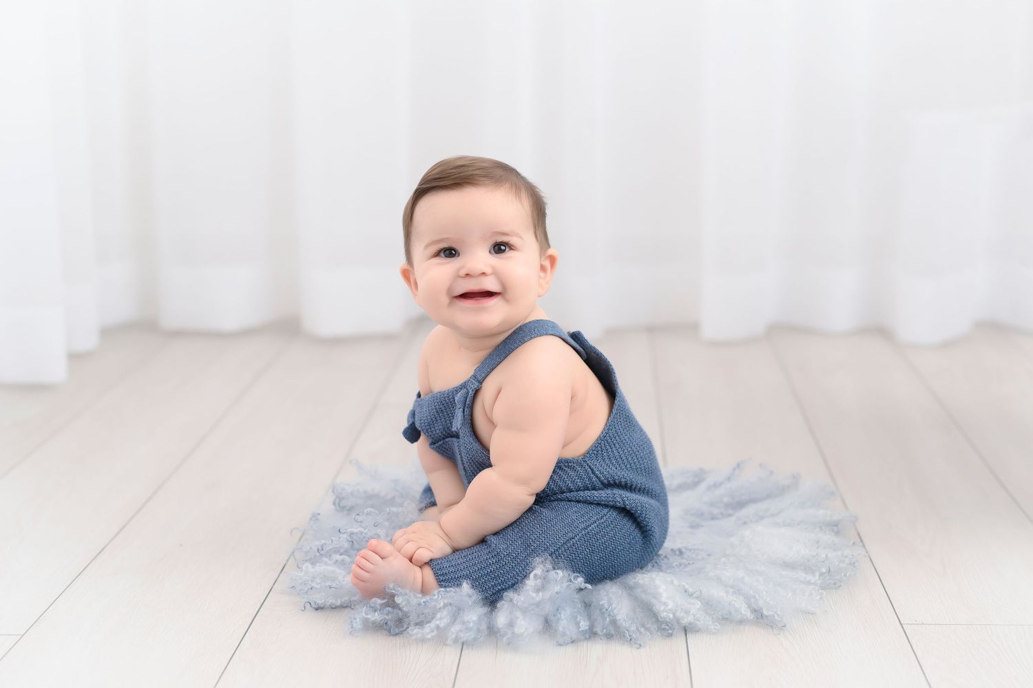 baby boy on blue fur with blue overalls
