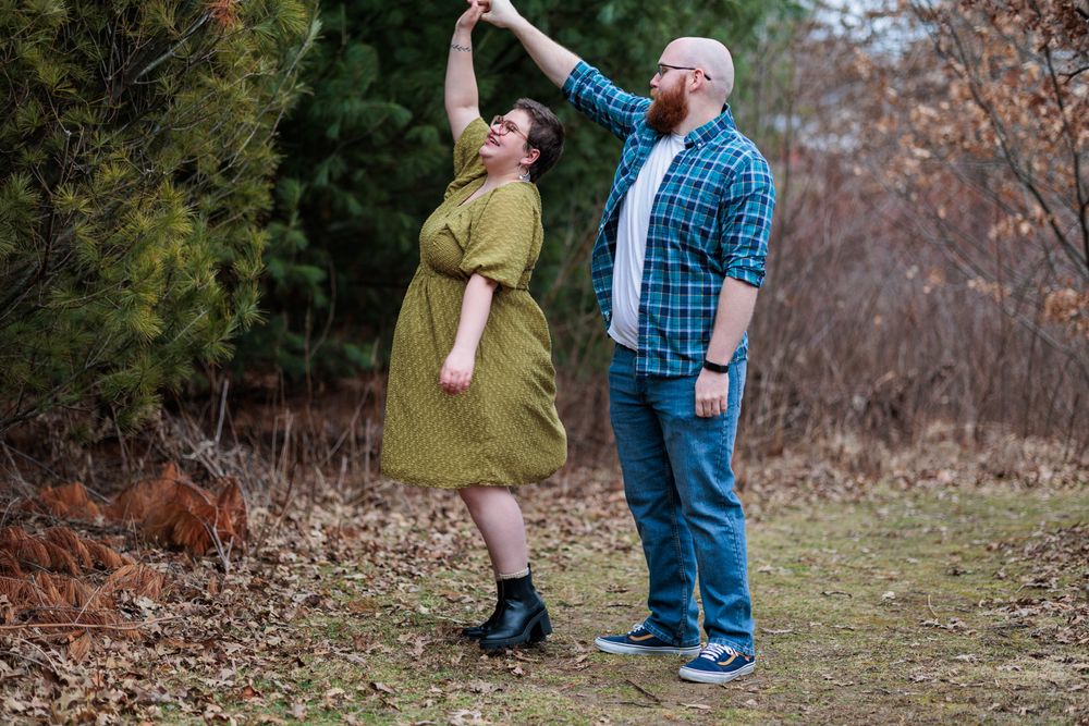 A couple in casual attire shares a tender moment together outdoors during an autumn photoshoot.