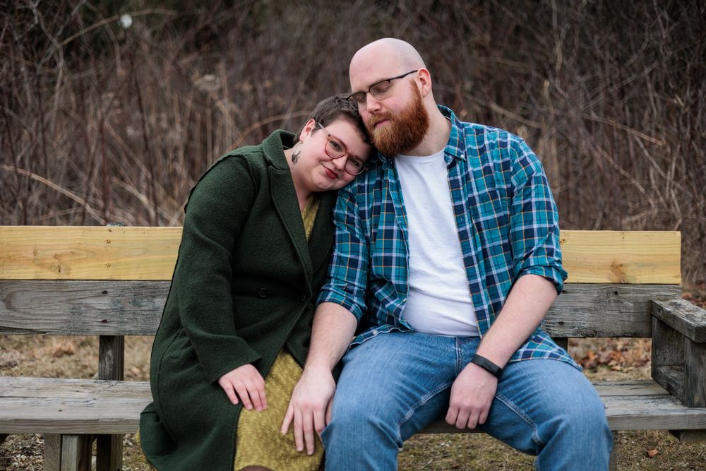A couple shares a romantic moment while sitting on a wooden bench at Beckenholdt Park.
