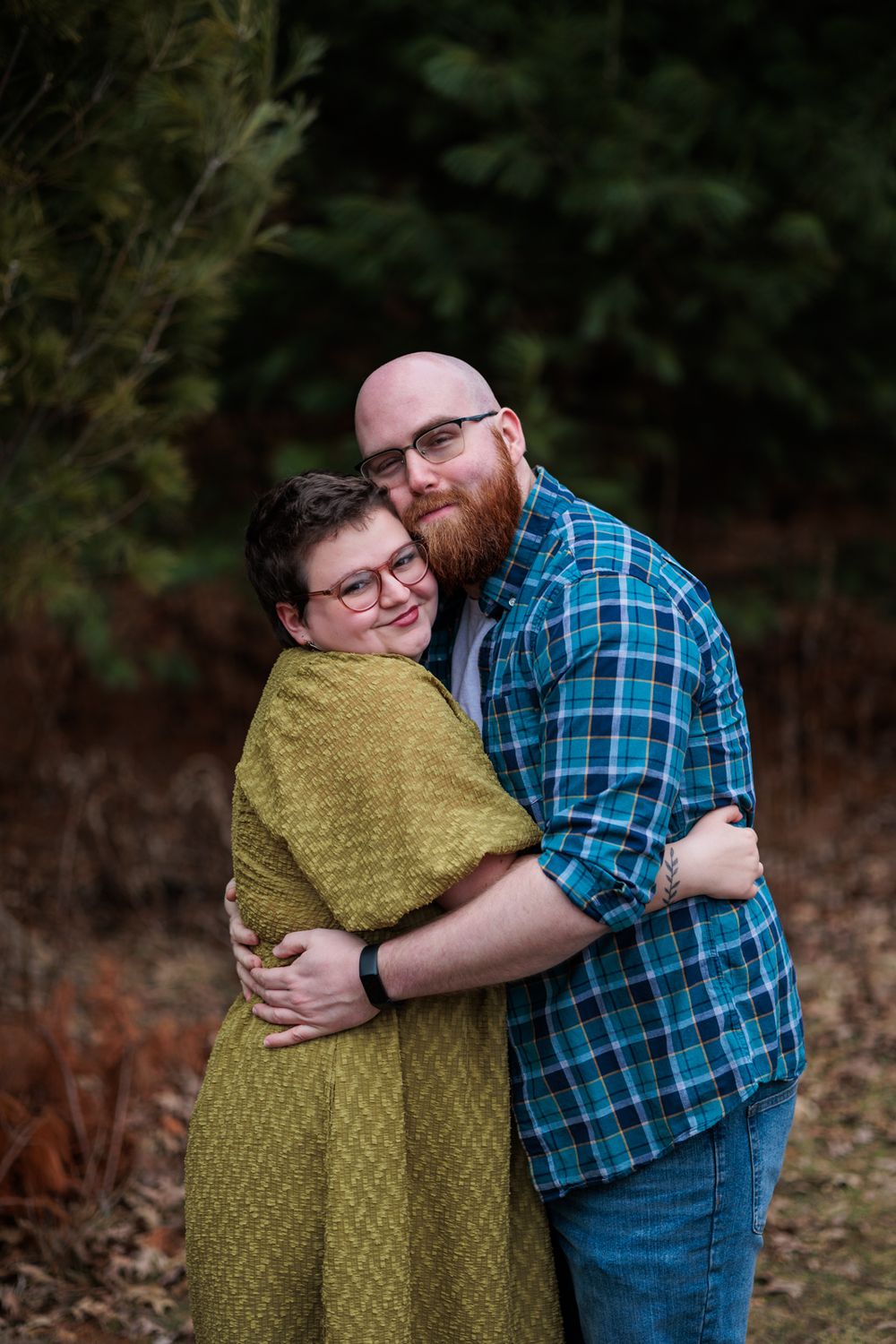 Two people share an intimate hug while wearing contrasting outfits of olive green and blue plaid.