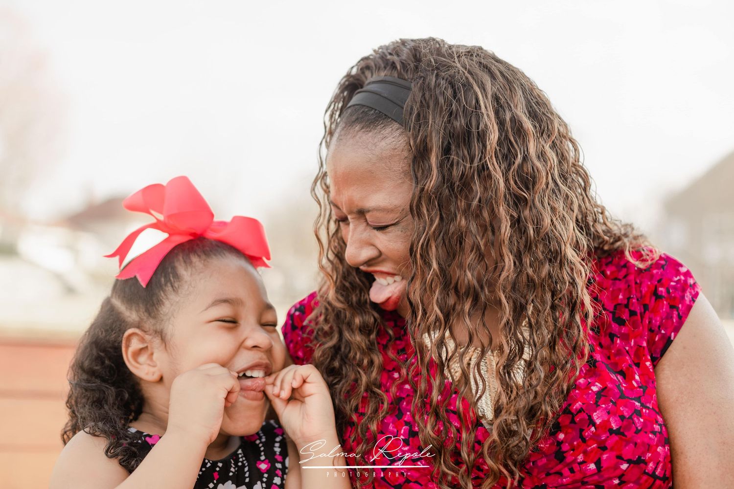 Two people in red polka dot dresses share joyful moments together outdoors.