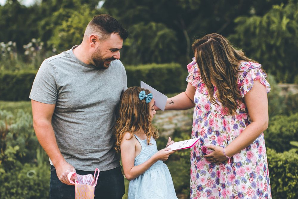 Family standing together outdoors exchanging gifts in a garden.