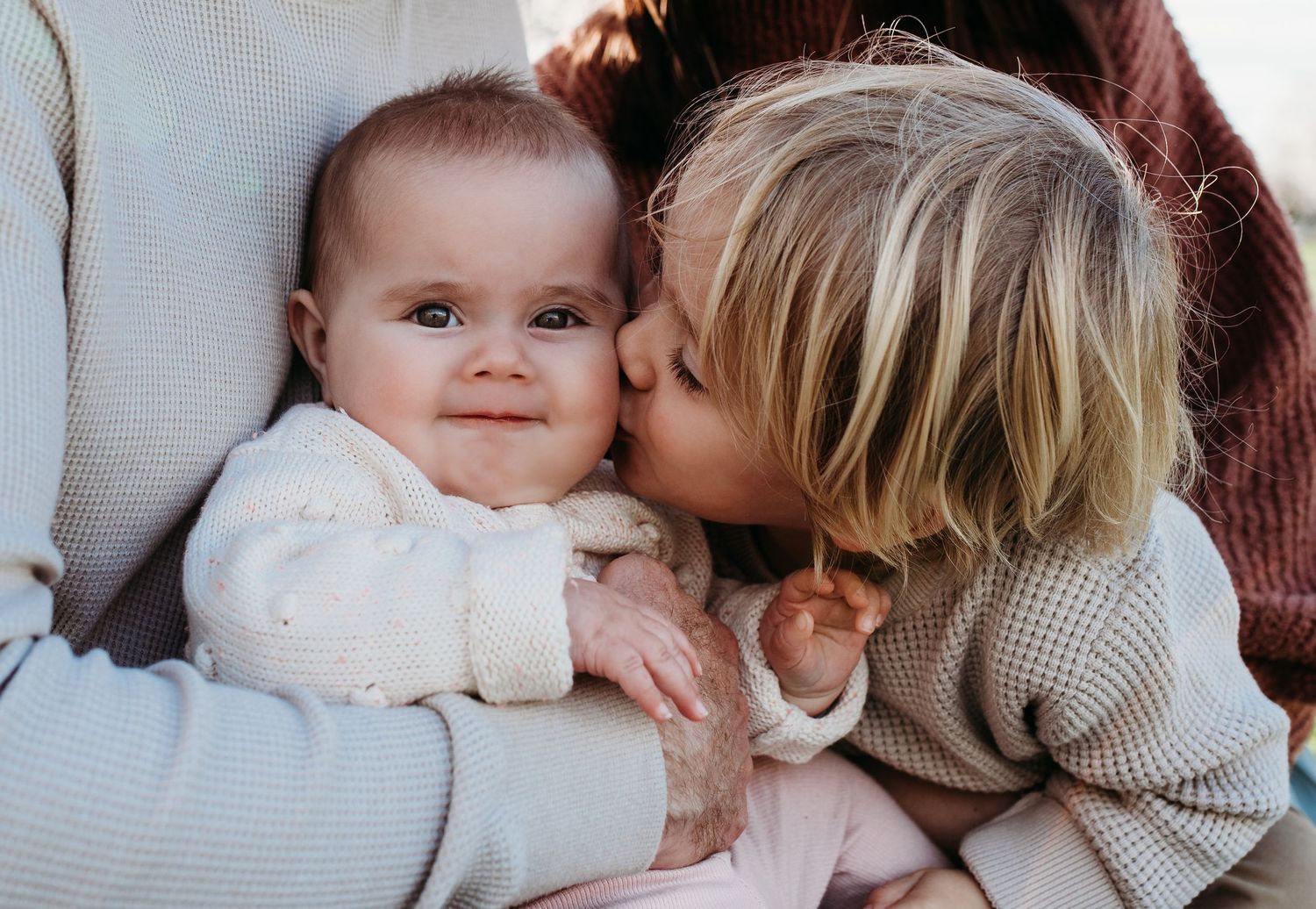 Outdoor family photoshoot in a blooming spring orchard with soft natural lighting.