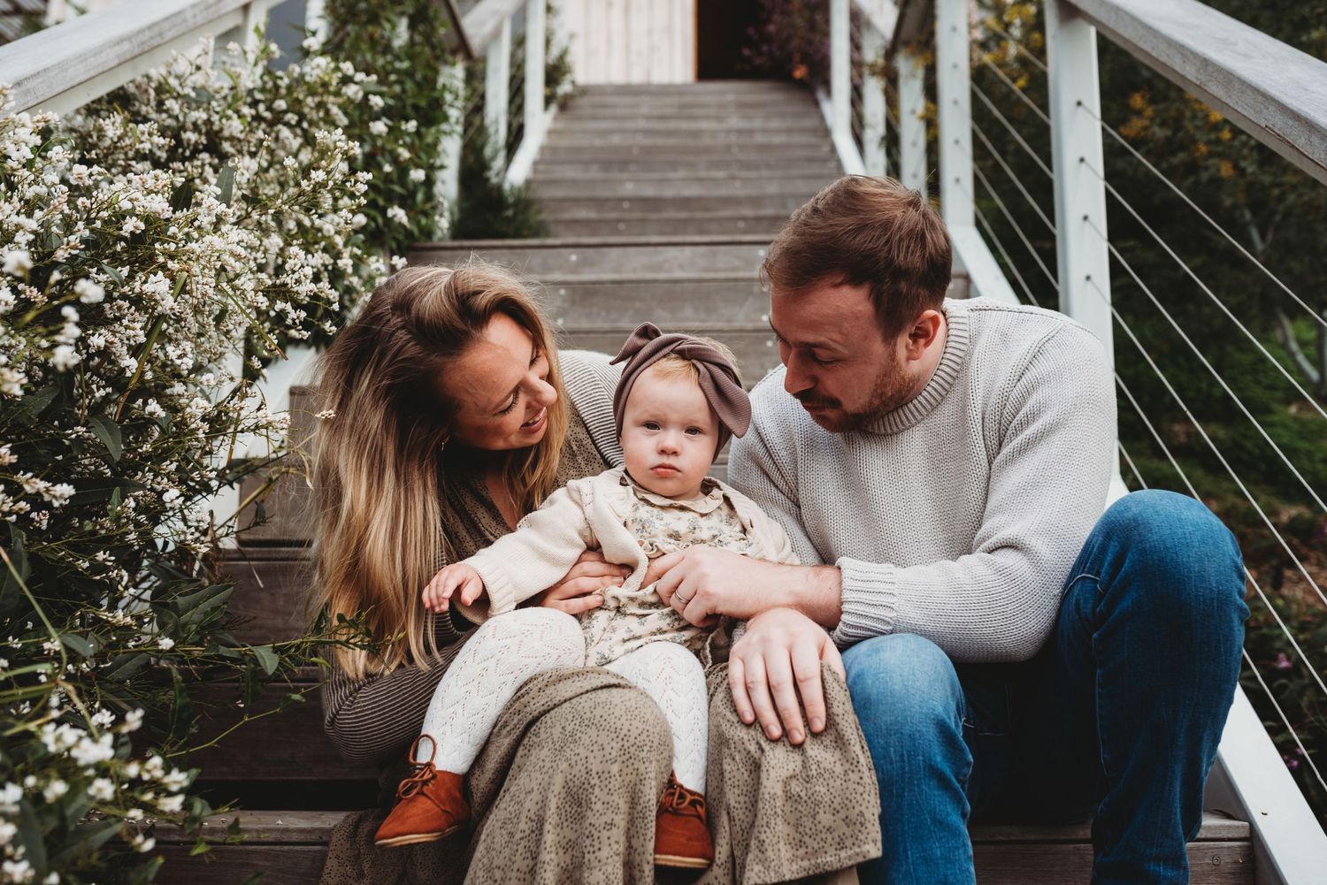Family portrait session on white porch with blooming spring flowers in background.