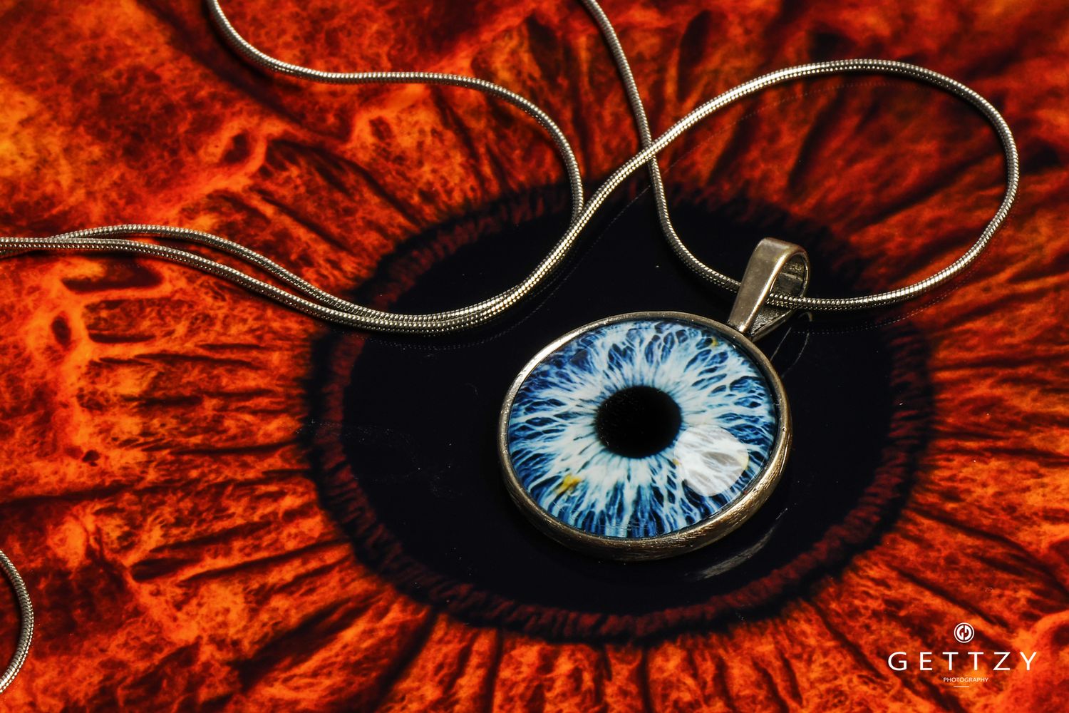 Blue eye pendant necklace displayed on red textured background.