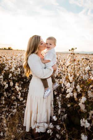 A mom gives kisses to her baby in the cotton fields at sunset in Arizona.