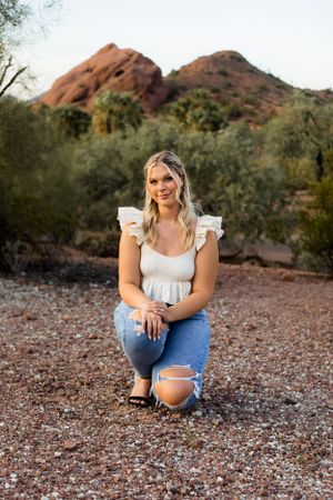 Papago park mountain view in Arizona for this young senior graduate girl whos sitting and casually dressed while smiling at the camera.