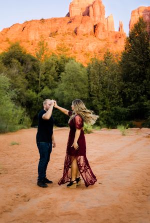 A couple dancing and spinning in front of the Sedona red rock mountain for their engagement portrait session.