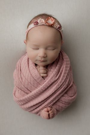 Perfectly pink swaddled newborn baby girl posed on a white background for her studio newborn session in Scottsdale.