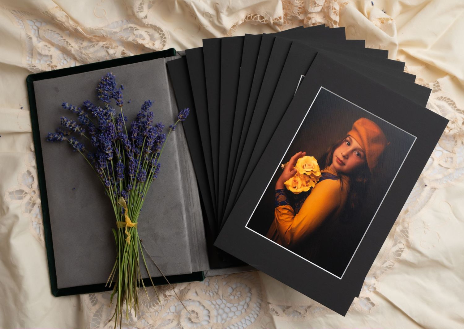 Black matted prints and fresh lavender sprigs arranged on cream colored fabric.