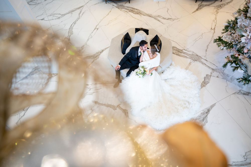 Bride and groom sitting on the sofa, showing off the bride's well-arranged dress for the photo. Long Island Wedding