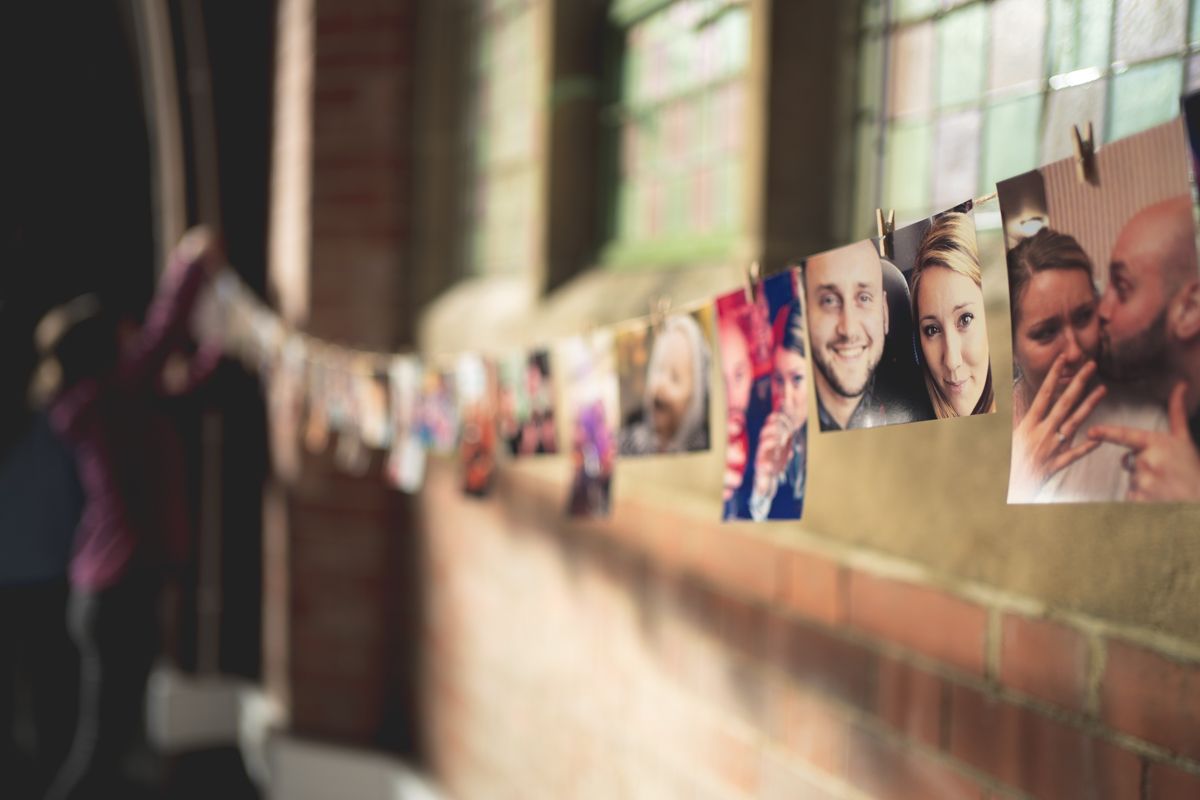 A string of photographs hangs across a sunlit window display or wall.