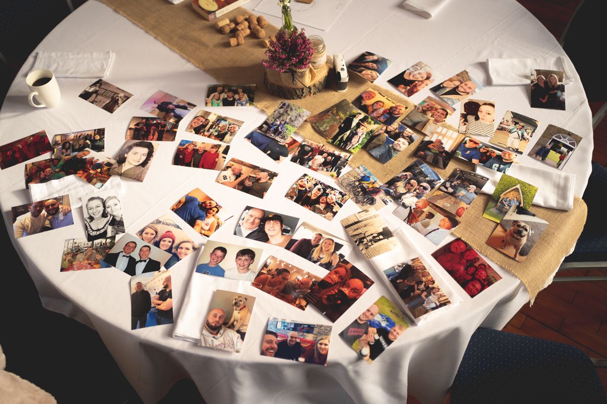 Multiple photographs spread across a white round table at what appears to be an event or gathering.