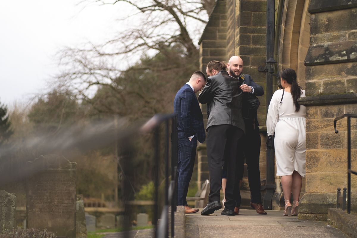 Group gathered outside stone church building on overcast day.