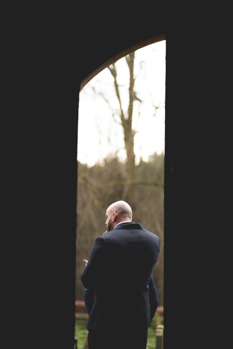 Silhouetted figure in coat viewed through doorway against bright background.