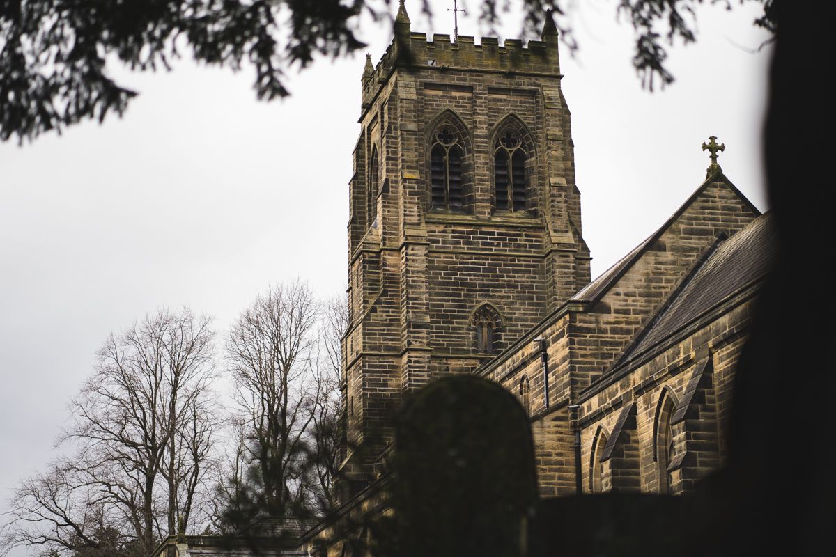 Gothic stone church tower with ornate architecture photographed against an overcast sky.