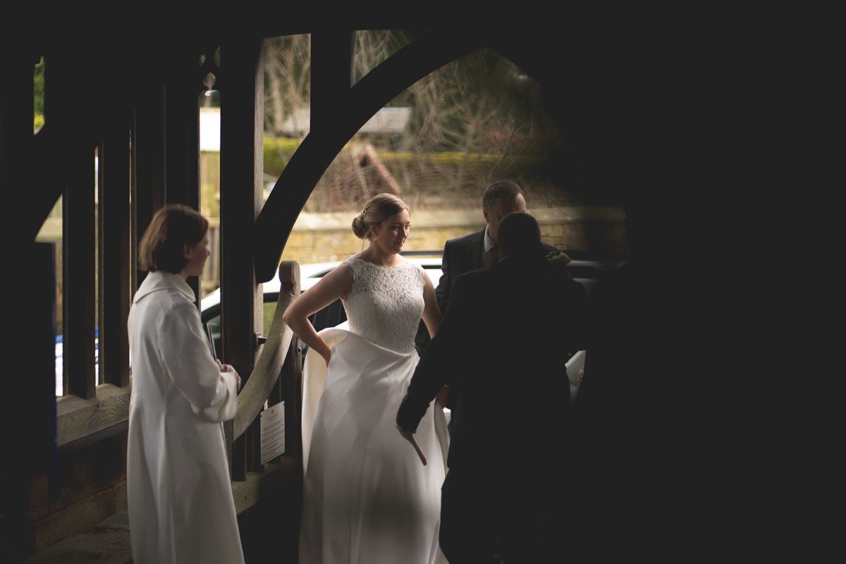 Silhouettes of people gathered under an archway in formal white attire.