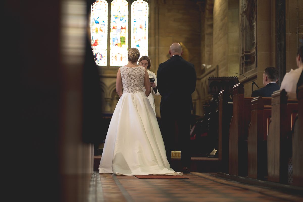 A wedding ceremony taking place in a traditional church with stained glass windows.