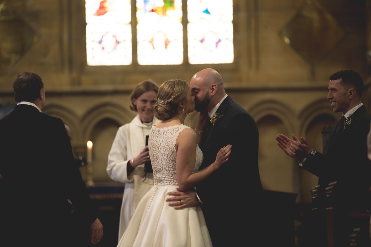 Wedding ceremony moment captured inside historic church with stained glass windows.