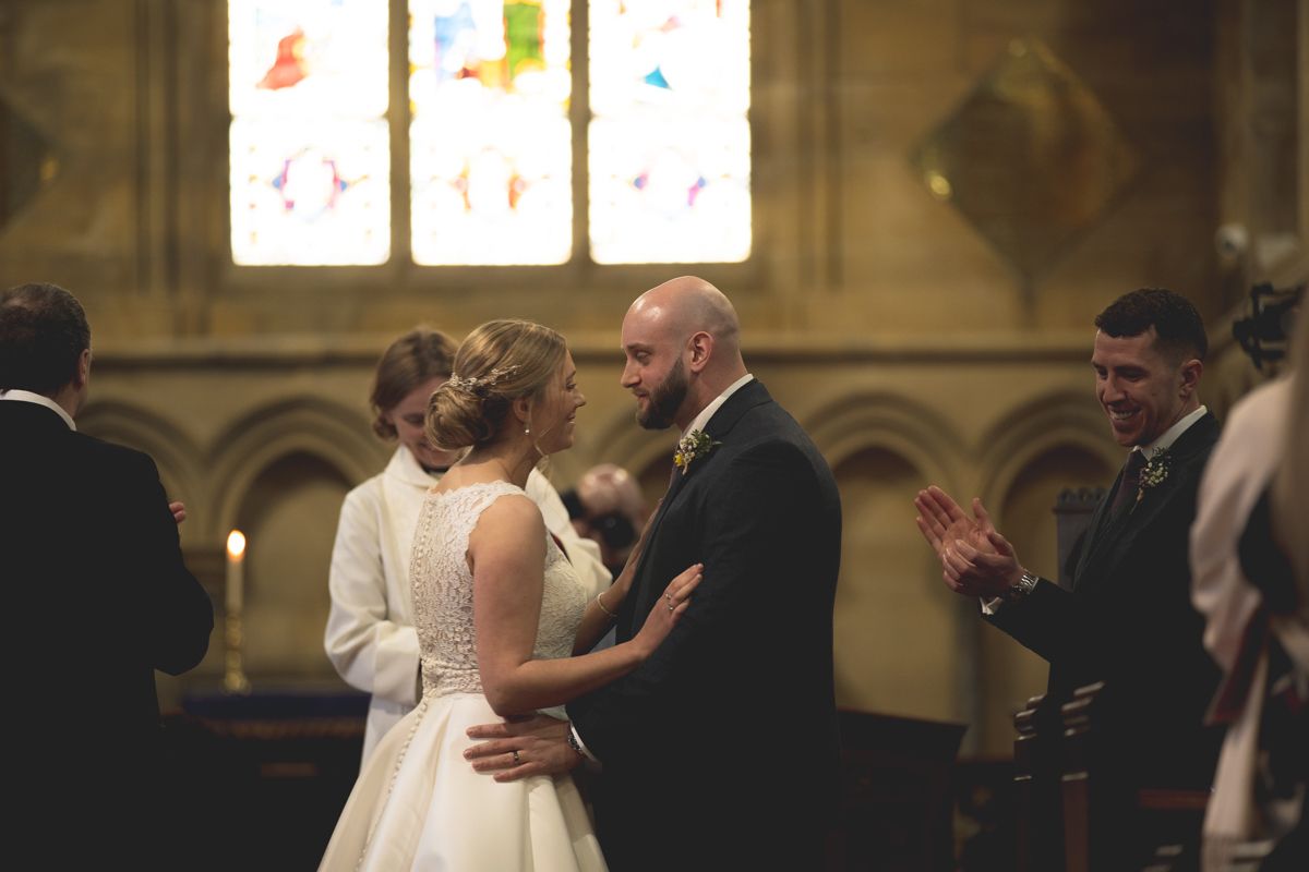 Intimate wedding ceremony moment in a historic church with decorative windows.