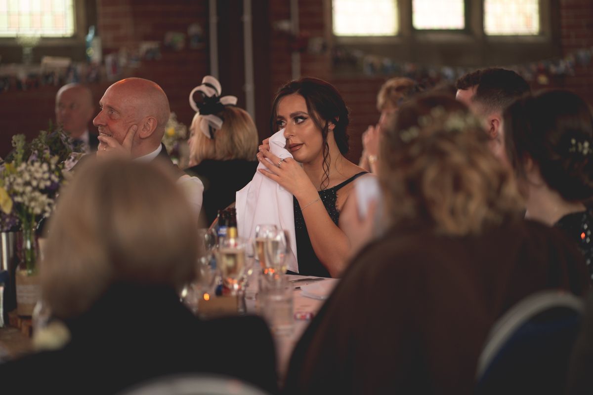 A guest at a formal event covers their mouth in reaction during dinner.