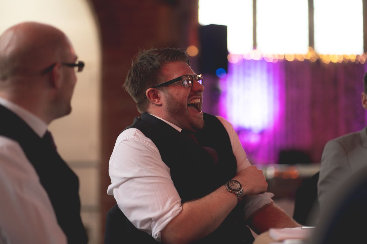 A guest laughs heartily during a wedding reception celebration.