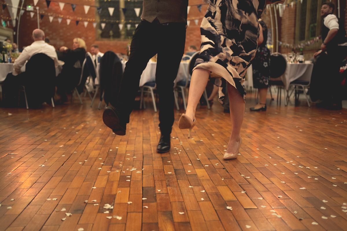 Dancers move energetically on a wooden dance floor decorated with bunting flags above.